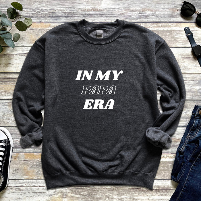 a sweater that says in my papa era next to a pair of jeans